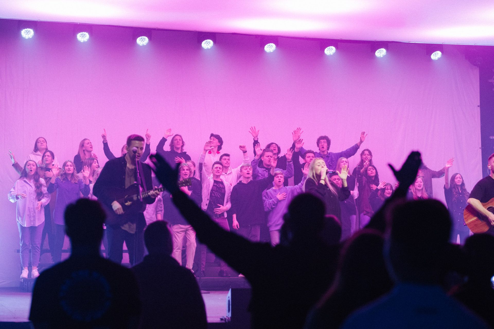 Worship team and choir leading worship on stage at Church of Truth in Vancouver, WA as the congregation raises their hands
